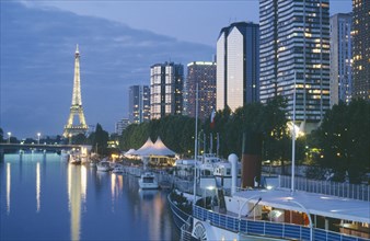 FRANCE, Ile de France, Paris, Le Front de Seine with the Eiffel Tower behind illuminated at dusk.