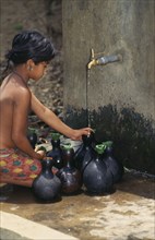 BANGLADESH, Water, Mrong girl fetching water from outside tap in small flasks.