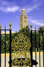 MOROCCO, Marrakech, View through black and gold wrought iron gate towards the minaret of Koutoubia