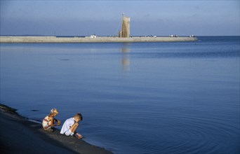 LITHUANIA, Nida, Baltic coastal resort.  Children playing at the edge of water.