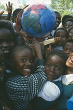 MALAWI, Blantyre, School children with globe made by Pamet paper making project which produce fair