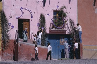 MEXICO, Guanajuato, San Miguel de Allende, People decorating exterior of house with palm fronds and