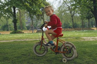CHILDREN, Playing, Outdoor, Three year old boy learning to ride a bicycle using stabilizers