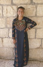 WEST BANK, People, Young woman in traditional Palestinian embroidered dress in National colours