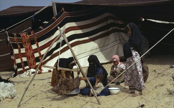 QATAR, People, Bedouin women and children sitting on sand outside tent