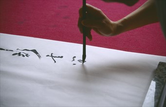 CHINA, Sichuan, Leshan, Cropped view of person writing traditional Chinese caligraphy.
