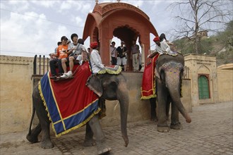 INDIA, Rajasthan, Jaipur, Japanese tourists taking elephant ride with mounting platform behind them