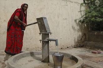INDIA, Rajasthan, Jaipur, Woman filling bucket at Tare water pump