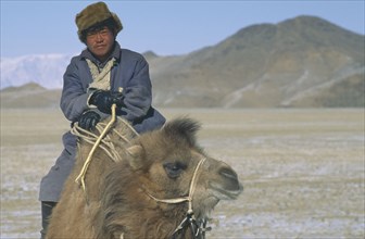 MONGOLIA, Hovd Province, Mongol nomad returning to camp on camel back