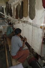 INDIA, Rajasthan, Jaipur, Boys weaving a Rajastan carpet on a large loom