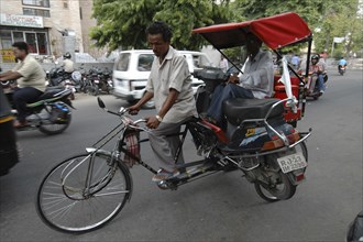 INDIA, Rajasthan, Jaipur, Cycle rickshaw transporting passenger and motorbike