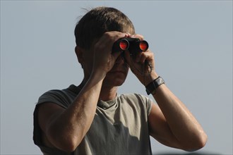 ROMANIA, Tulcea, Danube Delta Biosphere Reserve, Male tourist with binoculars with scenery