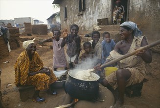 GHANA, Near Accra, Women and children cooking Fufu the national delicacy of pounded yams in a small