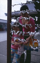 JAPAN, Honshu, Tokyo, Asakusa. Woman and girl tying Omikuji or Fortune papers at Senso Ji Temple