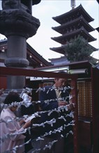 JAPAN, Honshu, Tokyo, Asakusa. People tying Omikuji or Fortune papers at Senso Ji Temple