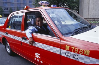 JAPAN, Honshu, Tokyo, Red Taxi cab with driver looking out of open window