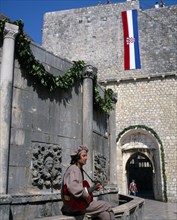 CROATIA, Dalmatia, Dubrovnik, Onofrio fountain and man in costume playing a guitar