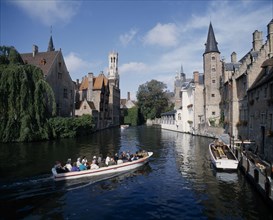 BELGIUM, West Flanders, Bruges, Rozenhoed Belfry. View down canal with tourists traveling on boats.