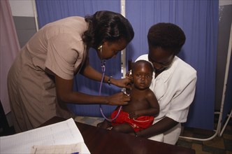 UGANDA, Kampala, Woman doctor examing infant at Kawempe clinic
