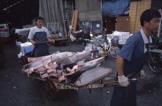 JAPAN, Honshu, Tokyo, Tsukiji Fish Market with men transporting cut Tuna on a cart