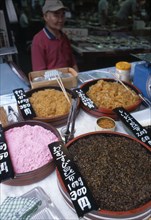 JAPAN, Honshu, Tokyo, Tsukiji Fish Market stall with variety of seafood items on dispay and vendor