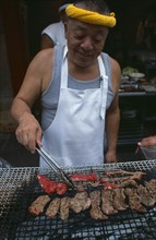 JAPAN, Honshu, Tokyo, Tsukiji Fish Market. Man cooking red meat on an open grill
