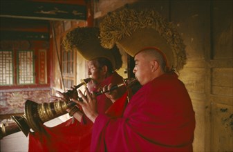 CHINA, Qinghai, Queshang Lamasery, Yellow hat Buddhist Monks playing horn instruments in the temple