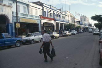 CARIBBEAN, Jamaica, Kingston, Man crossing King Street towards parked cars and shops