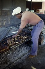 WEST INDIES, Jamaica, "Food	", Man cooking jerk pork over an open fire