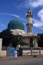 NIGERIA, Kano, Mosque with green dome. Man stood outside the open gate.