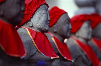 JAPAN, Honshu, Kamakura, View along row of Jizo statues dressed in red bibs by bereaved mothers and