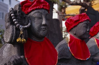 JAPAN, Honshu, Kamakura, Row of Jizo statues dressed in red bibs by bereaved mothers and other