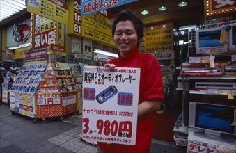 JAPAN, Honshu, Tokyo, Akihabara Electronics District. Vendor holding poster outside his electrical