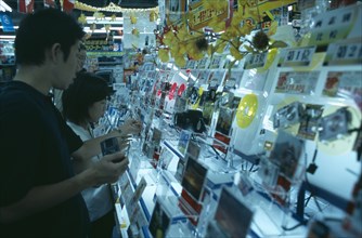 JAPAN, Honshu, Tokyo, Shinjuku. Customers browsing in Camera shop interior with illuminated