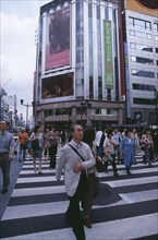 JAPAN, Honshu, Tokyo, Ginza. Busy pedestrian crossing with city architecture behind