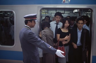 JAPAN, Honshu, Tokyo, Passengers on crowded train at Ueno Station with train guard standing on the