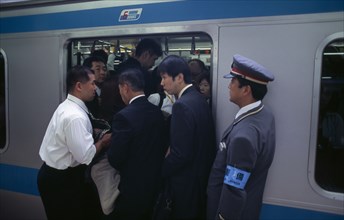 JAPAN, Honshu, Tokyo, Passengers crowding on to a train at Ueno Station with train guard standing