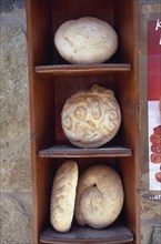 GREECE, Peloponnese, Traditional breads displayed on wooden shelves.