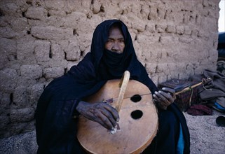NIGER, General, Tuareg woman playing an Imzad.  A traditional instrument consisting of a goatskin