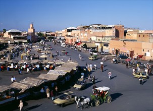 MOROCCO, Marrakech, Djemaa El Fina Square. View over busy market square with people at stalls and