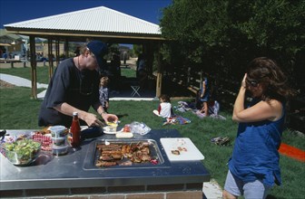 AUSTRALIA, New South Wales, Sydney, Young couple having barbecue at Dee Why beach in North Sydney.