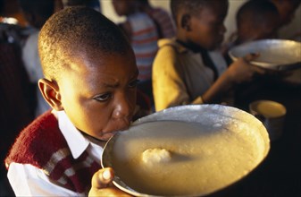 TANZANIA, Singida, Boy drinking from bowl of breakfast at the Kititimo Centre School for street