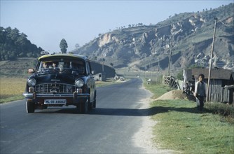 INDIA, Meghalaya, Packed ambassador taxi on road through rural area in north east India.