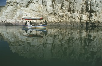 INDIA, Madhya Pradesh, Marble Rocks, Painted tourist boat on the Narmada River passing sheer cliffs