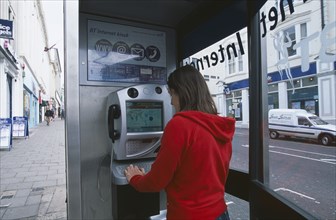COMMUNICATIONS, Phone Box, Young woman using a public BT Internet phone booth.