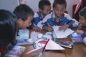 CHINA, Yunnan Province, Children in their classroom working in groups with various school materials
