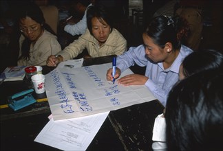 CHINA, Yunnan Province, Simao. Pu’er. Teachers sat around a table preparing a presentation on flip