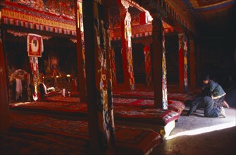 TIBET, Sakya, View through the interior of a temple in red ambient light towards the monks long