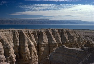 ISRAEL, Quamran, View over rocky eroded cliffs to the Dead Sea beyond