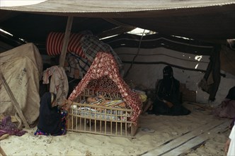 MIDDLE EAST, People, Bedouin desert encampment.  Woman and children inside tent with baby in